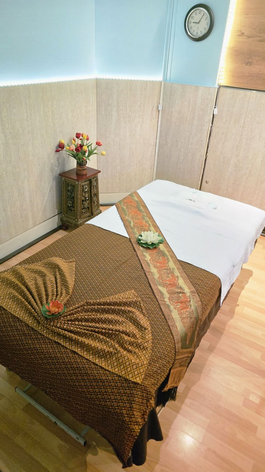 Massageliege mit Seidenläufer und frischen Blumen