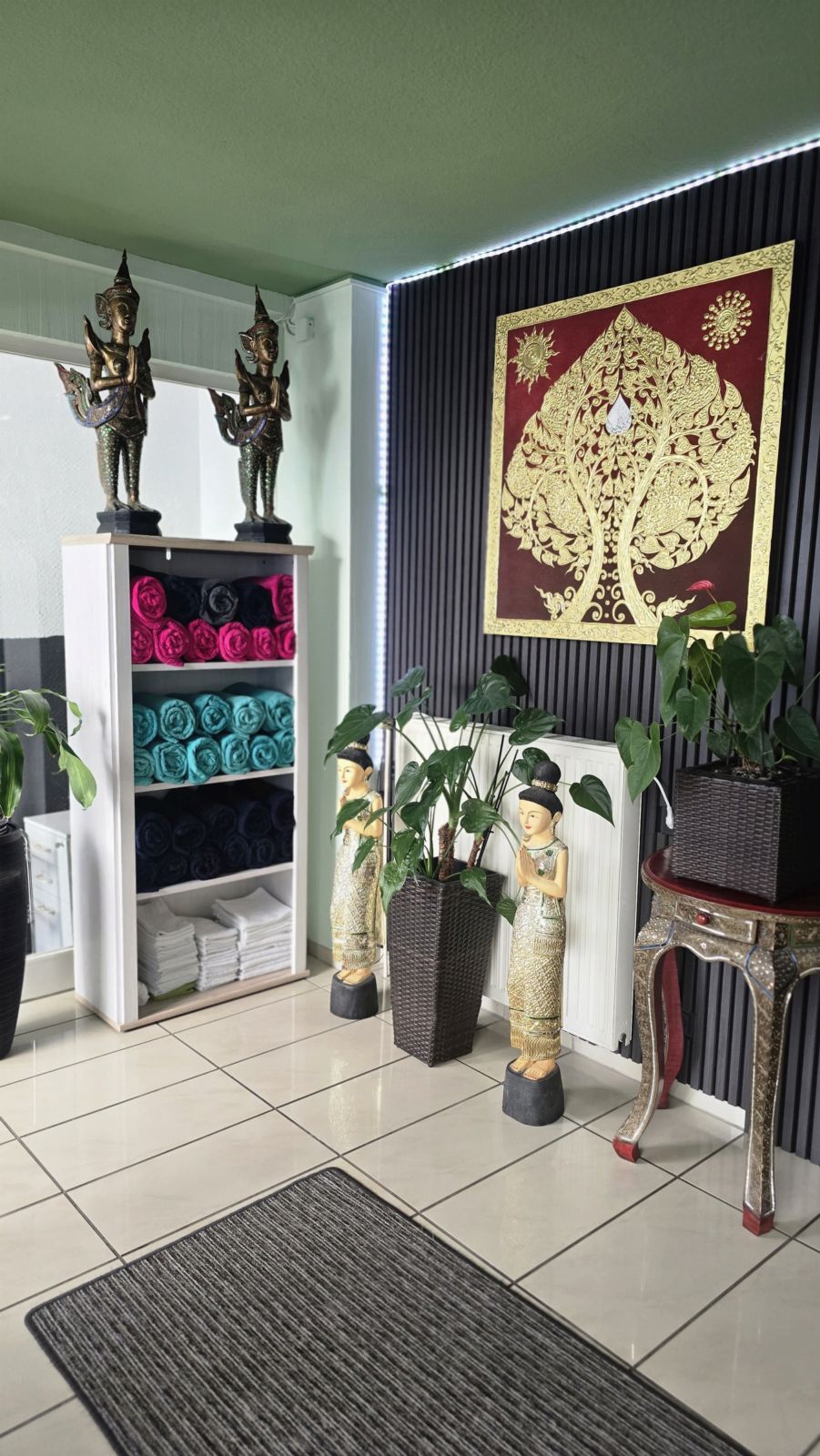 Thailändisches Wandbild, Buddha-Figuren und frische Handtücher